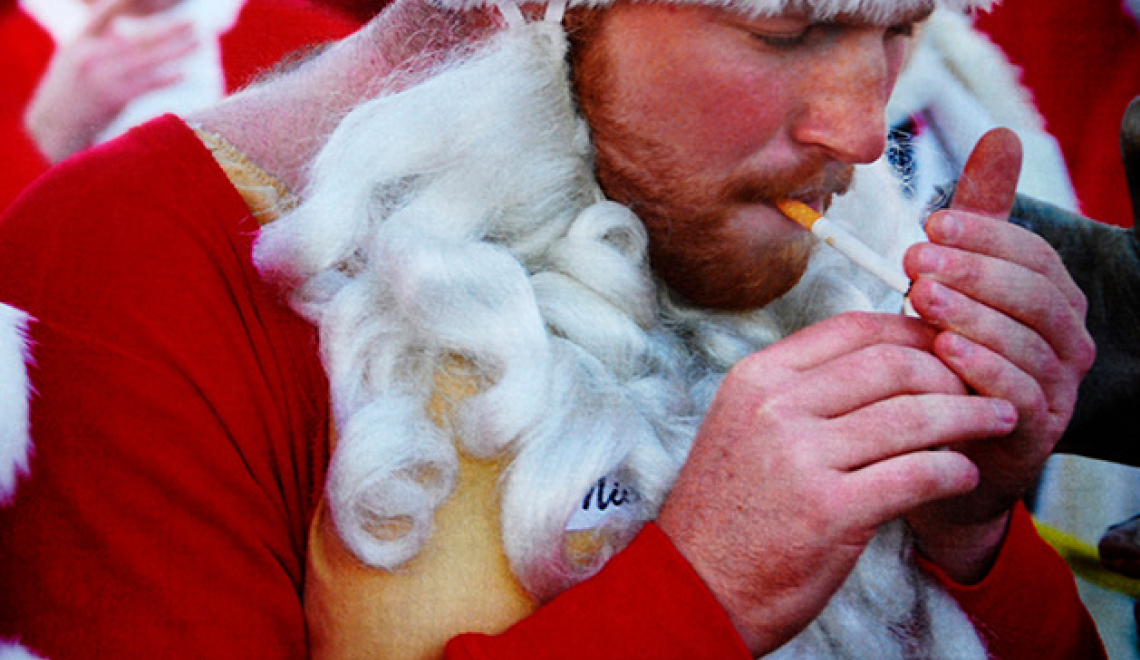 Man dressed as Santa Claus smoking a Cigarette - Jesse Millan - Wikipedia Abbildung von Mann verkleidet als Weihnachtsmann der raucht