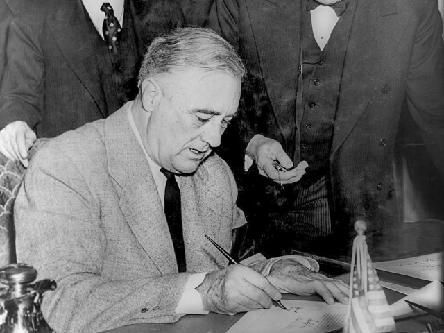 Abbildung des US President Franklin D. Roosevelt beim unterzeichnen des Dokuments zum Eintritt in den Zweiten Weltkrieg